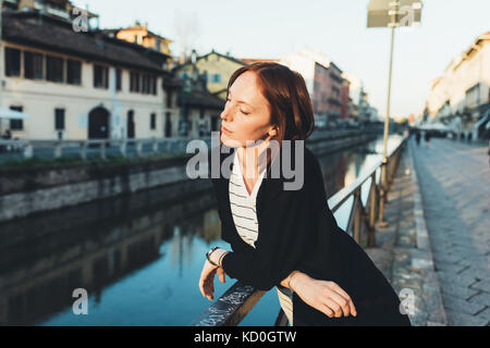 Giovane donna appoggiata contro la ringhiera guardando in giù a canal Foto Stock