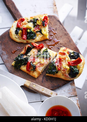 Pancetta, carciofi e cicorie pizza sul servizio di amministrazione, vista in elevazione Foto Stock