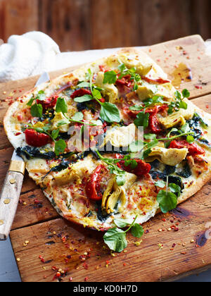 Pancetta, carciofi e cicorie pizza sulla scheda servente, close-up Foto Stock