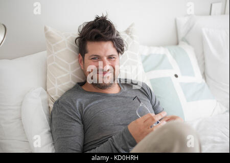Ritratto di metà uomo adulto giacente sul letto rilassante sul letto Foto Stock