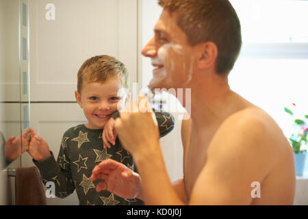 Ritratto di ragazzo in bagno con padre la rasatura Foto Stock