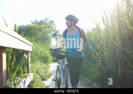 Ciclista walking bici sul percorso attraverso erba alta Foto Stock