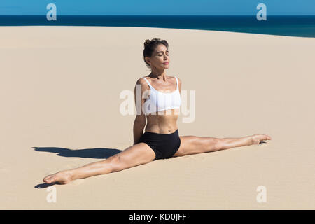 Donna sulla spiaggia in posizione di yoga, i gruppi Foto Stock