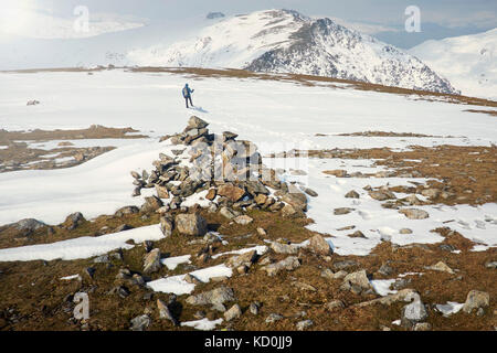 Escursionista sulla coperta di neve montagna, Coniston, Cumbria, Regno Unito Foto Stock