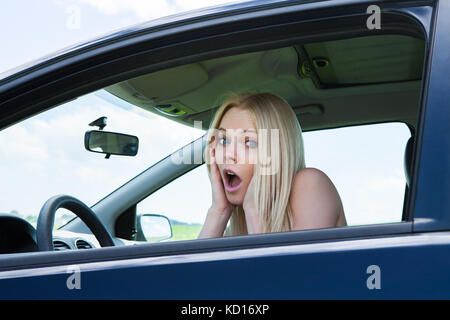 Ritratto di donna frustrata urlando seduti in auto Foto Stock