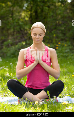 Ritratto della giovane donna bionda che pratica lo Yoga nel Parco Foto Stock