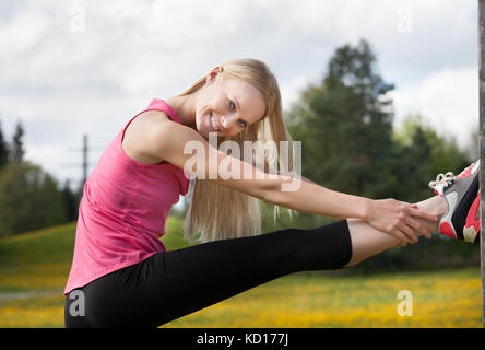 Ritratto di giovane felice donna bionda gamba di stiramento Foto Stock