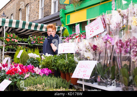 Giovane uomo vendita di fiori e piante in un esterno di stallo nella famosa columbia road flower market, vicino a Hackney Road, Tower Hamlets, East London, Regno Unito. Foto Stock