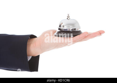 Close-up di persona della mano che tiene la campana di servizio su sfondo bianco Foto Stock