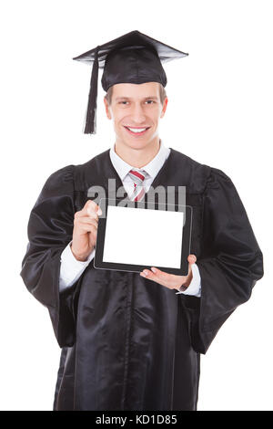 Giovane uomo in veste di graduazione che mostra vuoto Tablet Pc su sfondo bianco Foto Stock