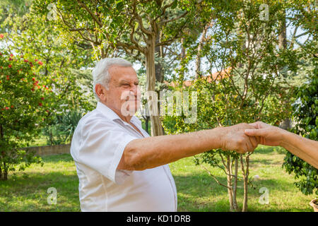 Old man mano tremante nel giardino verde Foto Stock