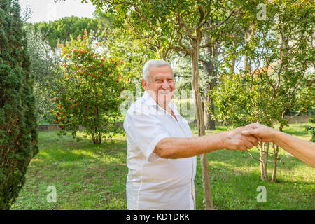Old man mano tremante nel giardino verde Foto Stock
