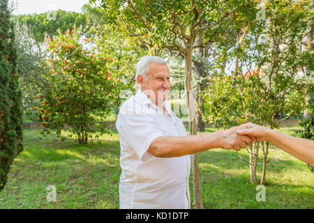 Old man mano tremante nel giardino verde Foto Stock
