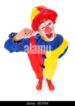 Elevato angolo di visione di un clown inserendo le dita in orecchio su sfondo bianco Foto Stock