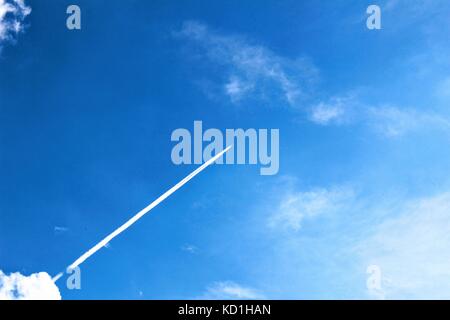 Contrail da un aereo su un cielo blu chiaro. Foto Stock