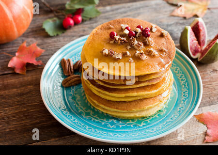 Frittelle di zucca con noci pecan bacche rosse e miele su un blu-turchese piastra. stagionale di cibo di autunno Foto Stock