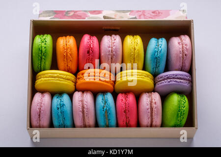 Amaretti colorati in una confezione regalo su sfondo grigio. Dolce macarons. Foto Stock