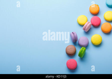 Una foto di colorati macarons, ripresa dall'alto su uno sfondo blu , con un posto per il testo Foto Stock