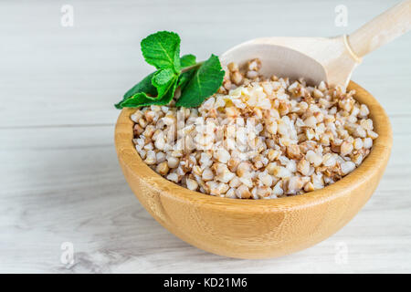 Farinata di grano saraceno in una ciotola di legno su una tavola di legno. Foto Stock