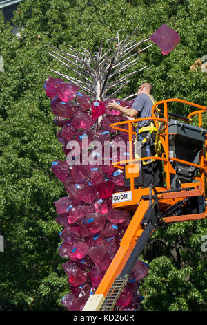 Un operaio installazione di Dale Chihuly's Rose torre di cristallo sculture di vetro adiacente a Union Square Park di Lower Manhattan, New York City. Foto Stock