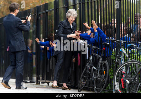 Embargo fino al 2230 lunedì 9 ottobre il primo ministro Theresa May è accolto da studenti primari durante una visita alla Dunraven School di Streatham, a sud di Londra, prima della pubblicazione dei dettagli del Government's Race Exparity Audit. Foto Stock