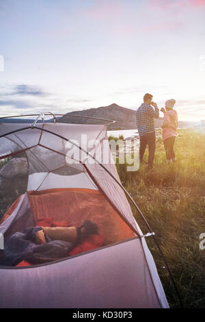 Matura in piedi vicino alla tenda, bere bevande calde, guardando a vista, Heeney, Colorado, Stati Uniti Foto Stock