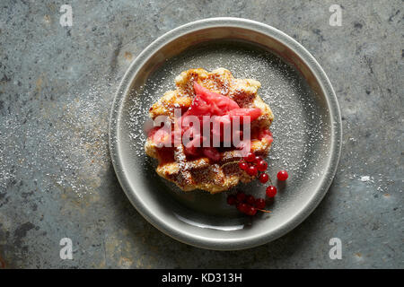 Waffle con fragole e rabarbaro marmellata, ribes rosso e zucchero a velo Foto Stock