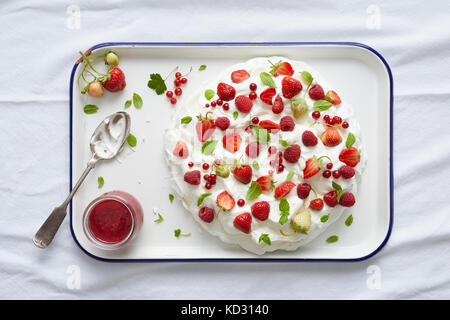 Pavlova con ribes rosso, fragola e menta fresca sul piatto di portata Foto Stock