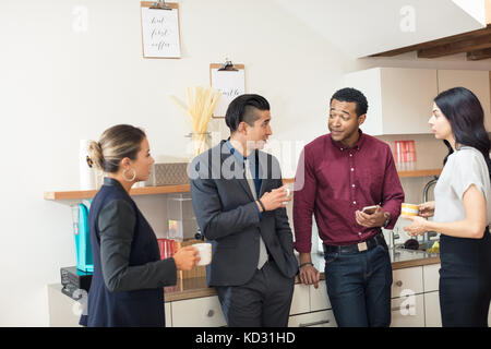 Imprenditrici e uomini avente una riunione informale in cucina per ufficio Foto Stock