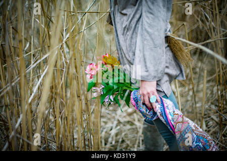 Donna con fiori tra l'erba alta Foto Stock