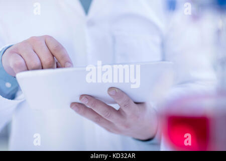 Lavoratore di laboratorio utilizzando digitale compressa, metà sezione Foto Stock