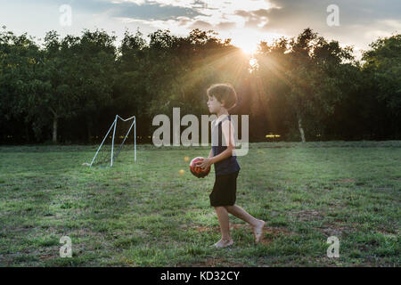 Ragazzo giocando a calcio in posizione di parcheggio Foto Stock