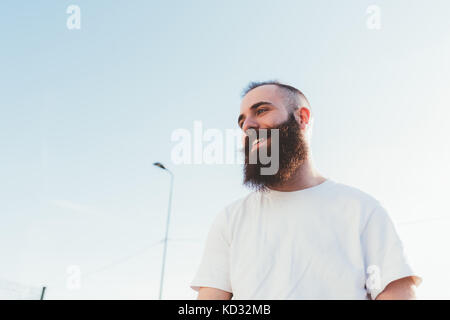 Ritratto di uomo barbuto che guarda lontano sorridente Foto Stock