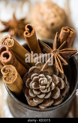 Natale la cottura Ingredienti bastoncini di cannella anice star noci chiodi di garofano pigna in caraffa vintage su uno sfondo di legno. Messaggio di saluto festivo card poster. nuovo Foto Stock