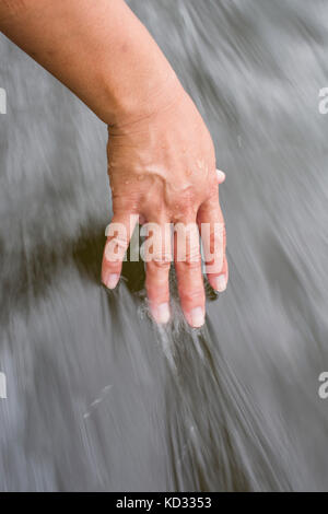 Donna trascinando la mano in acqua Foto Stock