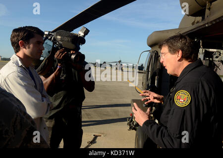 Tim Rodgers, a destra un elicottero di ricerca e salvataggio di piombo per la Carolina del Nord in Elicottero di salvataggio acquatico Team, rilascia un intervista con Blake Hanson, sinistra, reporter di WSOC basato su TV out di Charlotte mentre Carl McLean, medio, registrazioni video a McEntire comune di Guardia Nazionale Base, S.C., durante una statewide Flood response, Ottobre 8, 2015. La Carolina del Sud la Guardia Nazionale è stata attivata per il supporto di stato e contea di gestione di emergenza e le agenzie locali di prima emergenza come storico impatti di allagamento contee statewide. Attualmente più di 2.600 in Carolina del Sud la guardia nazionale i membri sono state acti Foto Stock