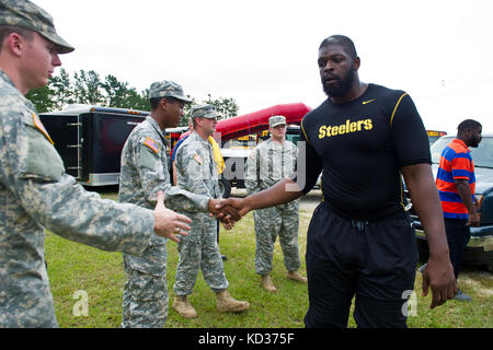 Il giocatore di NFL Clifton Geathers scuote le mani con i soldati dell'esercito degli Stati Uniti assegnati alla 1053esima compagnia di trasporti, South Carolina Army National Guard, come ringraziamento per averli aiutati a recuperare gli effetti personali della famiglia dalla loro casa allagata in Brown's Ferry vicino Georgetown, South Carolina, 10 ottobre 2015. La Guardia Nazionale del South Carolina è stata attivata per supportare le agenzie di gestione delle emergenze statali e della contea e i soccorritori locali, poiché le inondazioni storiche hanno un impatto sulle contee in tutto lo stato. Attualmente, più di 3,000 membri della Guardia Nazionale del South Carolina sono stati attivati in risposta alle inondazioni. (STATI UNITI Foto Stock