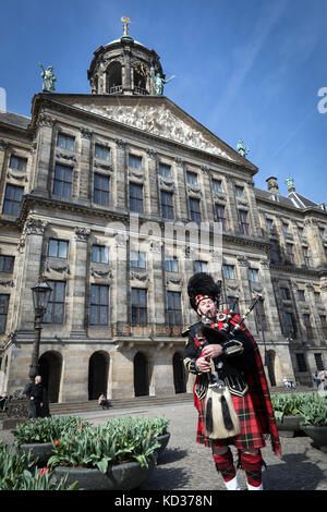 Un suonatore di cornamusa in costume scozzese incongruously svolge al di fuori del Palazzo Reale in Piazza Dam, Amsterdam Foto Stock