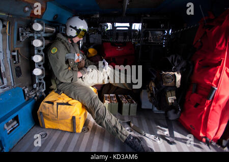 Il Crewman statunitense della Marina militare Mike Jones assegnato allo Squadron sottomarino Elicottero 11, si trova all'interno di un Seahawk HH-60H presso la base aerea navale di Jacksonville, Fla., 11 marzo 2014. Lo squadrone sta lavorando insieme al Battaglione di ricostruzione 151 dell'attacco, la Guardia Nazionale dell'Esercito del South Carolina, per addestrare sulla guerra di superficie e combattere la ricerca e il salvataggio in preparazione alla loro valutazione del programma di preparazione avanzata dell'elicottero. (STATI UNITI Air National Guard foto di Tech. SGT. Jorge Intriago/rilasciato) Foto Stock