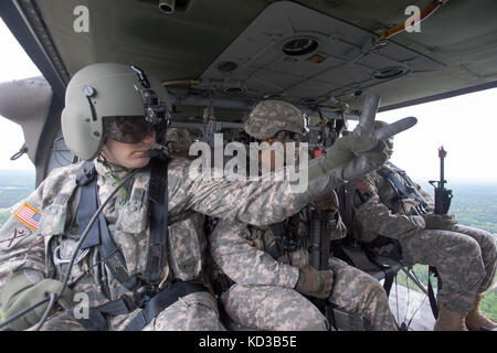 Us army sgt. Ryan dodd, un combattimento medic assegnato alla società f, 1-171st medevac, s.c. esercito nazionale guard, assiste l'equipaggio di volo con la Preparazione personale per lo sbarco sul campo hilton, Fort Jackson, s.c. 13 maggio 2015. quattro esercito usa uh-60 i falchi nero, assegnato alla società a, 1-111th aviazione generale del battaglione di supporto, s.c. esercito nazionale guardia, ha partecipato a una simulazione di assalto alla sfilata campo offrendo 29 trapanare sergenti da 1-34esimo reggimento di fanteria, allo scopo di catturare un nemico simulato posizione come parte di unità di base della formazione di combattimento cerimonia di laurea e per festeggiare Foto Stock