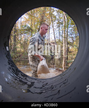 S.c. esercito nazionale guard spc. connor ulyatt con il 1221st engineering company da graniteville, s.c., assicura una sezione del canale sotterraneo di canalizzazione con sacchetti di sabbia come un team di ingegneri lavorano per sostituire un lavato fuori canale sotterraneo su lexington County road a Gilbert, s.c. oct. 24, 2015. soldati con la s.c. esercito guardia nazionale di continuare a fornire un sostegno diretto alle inondazioni e di ripristino di emergenza di riparazioni su strada come risultato delle recenti inondazioni. La Carolina del Sud la guardia nazionale collabora con federali, statali e locali di gestione delle emergenze le agenzie e i soccorritori. (L'esercito degli Stati Uniti Guardia nazionale foto di Sgt. br Foto Stock