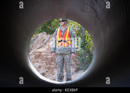 S.c. esercito guardia nazionale 1lt. benjamin sternemann con il 1221st engineering company da graniteville, s.c., dà istruzioni per l'escavatore idraulico operatore prima del sollevamento della sezione del canale sotterraneo di tubo come il suo team di ingegneri lavorano per sostituire un lavato fuori canale sotterraneo su lexington County road a Gilbert, s.c. oct. 24, 2015. soldati con la s.c. esercito guardia nazionale di continuare a fornire un sostegno diretto alle inondazioni e di ripristino di emergenza di riparazioni su strada come risultato delle recenti inondazioni. La Carolina del Sud la guardia nazionale collabora con federali, statali e locali di gestione di emergenza agenzie un Foto Stock