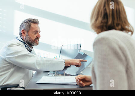 Medico specialista medico per discutere i risultati di scansione con paziente di sesso femminile nella sua clinica. Medico mostrando raggi x al paziente in ufficio medico. Foto Stock