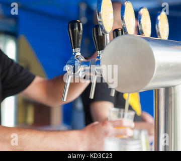 Barman mano alla birra tocca una colata di progetto birra chiara con sede di servizio in un ristorante o pub. Foto Stock