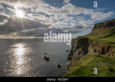 Tramonto al punto neist, isola di Skye in Scozia. drammatiche scogliere alte, sole riflessioni in acqua. Ebridi esterne a distanza Foto Stock