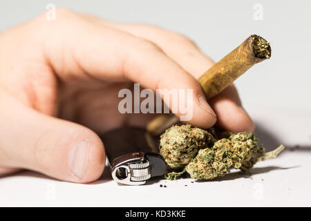 Mani su sfondo bianco tenendo un giunto di cannabis e marijuana. fumare marijuana addiction Foto Stock