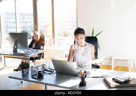 Due donne d'affari sul posto di lavoro. Due donne sedute in ufficio che lavorano insieme. Foto Stock