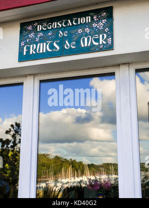 Il rustico ristorante di frutti di mare Francese segno pubblicità 'degustation de fruits de mer" (degustazione frutti di mare) con sky e il porto si riflette nella finestra Foto Stock