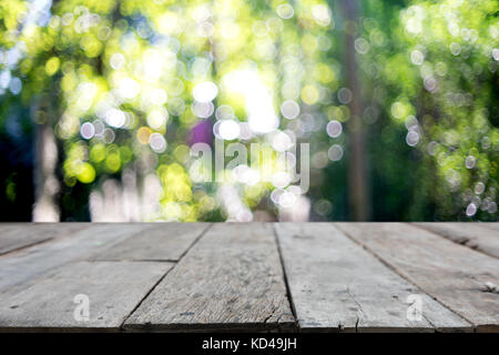 Tavolo in legno di fronte la sfocatura dello sfondo bokeh di fondo con la foglia verde tree Foto Stock