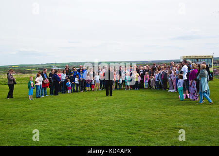 Un gruppo misto di persone, bambini e adulti che ascoltano un Storyteller presso le rovine dell'abbazia sulla cima delle scogliere sopra Whitby Town raccontando una storia sul Dr Foto Stock